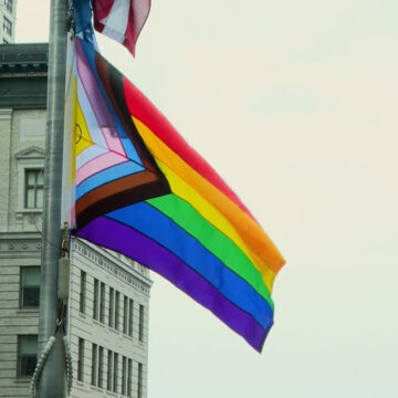 Pride Flag waving in the sky at City Hall