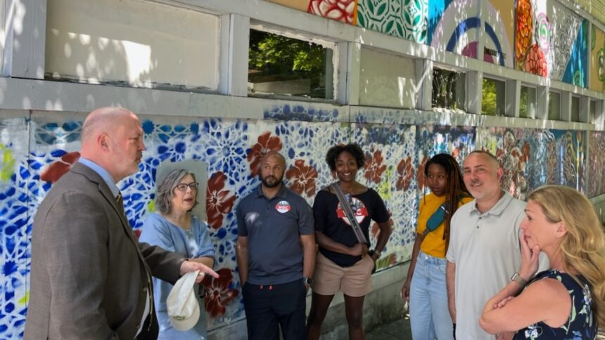a diverse group standing in front of a street mural, having a discussion