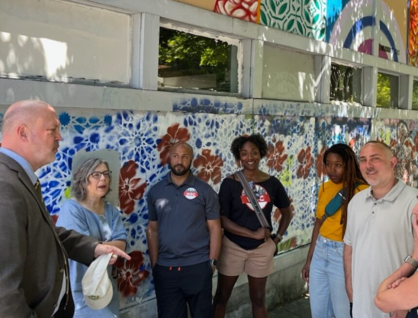 a diverse group standing in front of a street mural, having a discussion