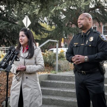 councilmember Rivera speaking into microphones with Police Chief Barnes standing next to her