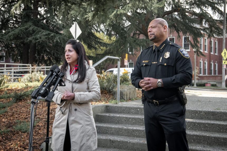 councilmember Rivera speaking into microphones with Police Chief Barnes standing next to her