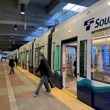 People get on and off an existing Sound Transit light rail train in Seattle