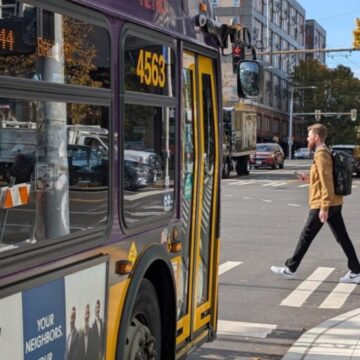 SDOT Bus bus stopped in front of a crosswalk as a person walks across