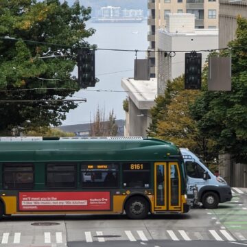 Bus driving through downtown Seattle, and the waterfront visible in the background