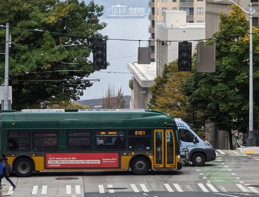 Bus driving through downtown Seattle, and the waterfront visible in the background