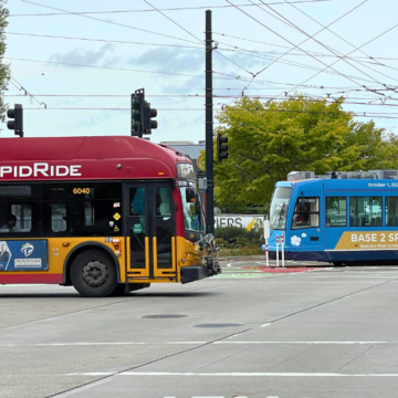 SDOT Bus and Streetcar A Red bus and a blue streetcar moving in opposite directions
