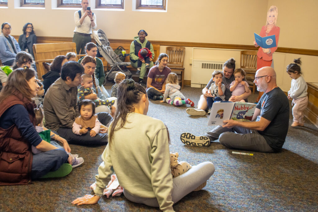 Author Dan Richards reads his book "Nubby" to children and adults sitting on the floor with him